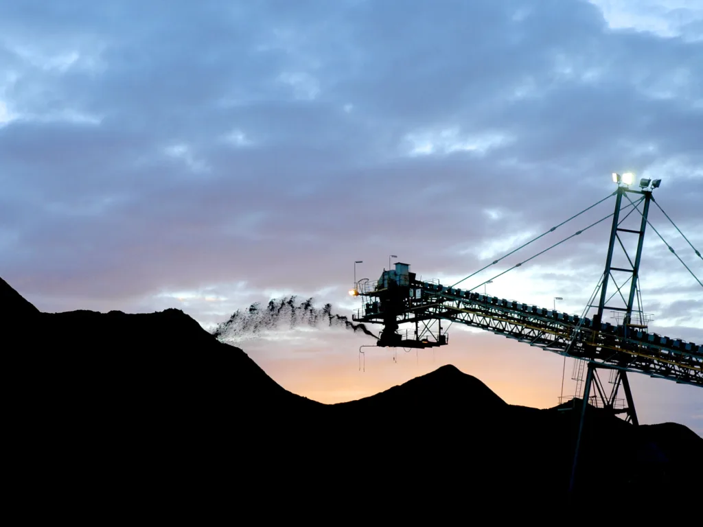A dusk shot of a conveyor dumping coal onto a stockpile